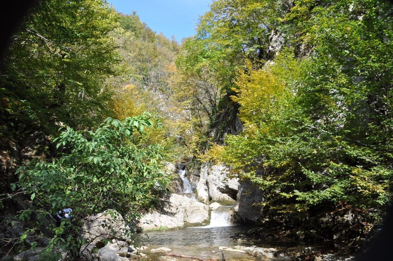 Bursa'daki Sansarak Kanyonu'nda kayaların arasından akan küçük bir şelale ve yemyeşil ağaçlarla çevrili dere.