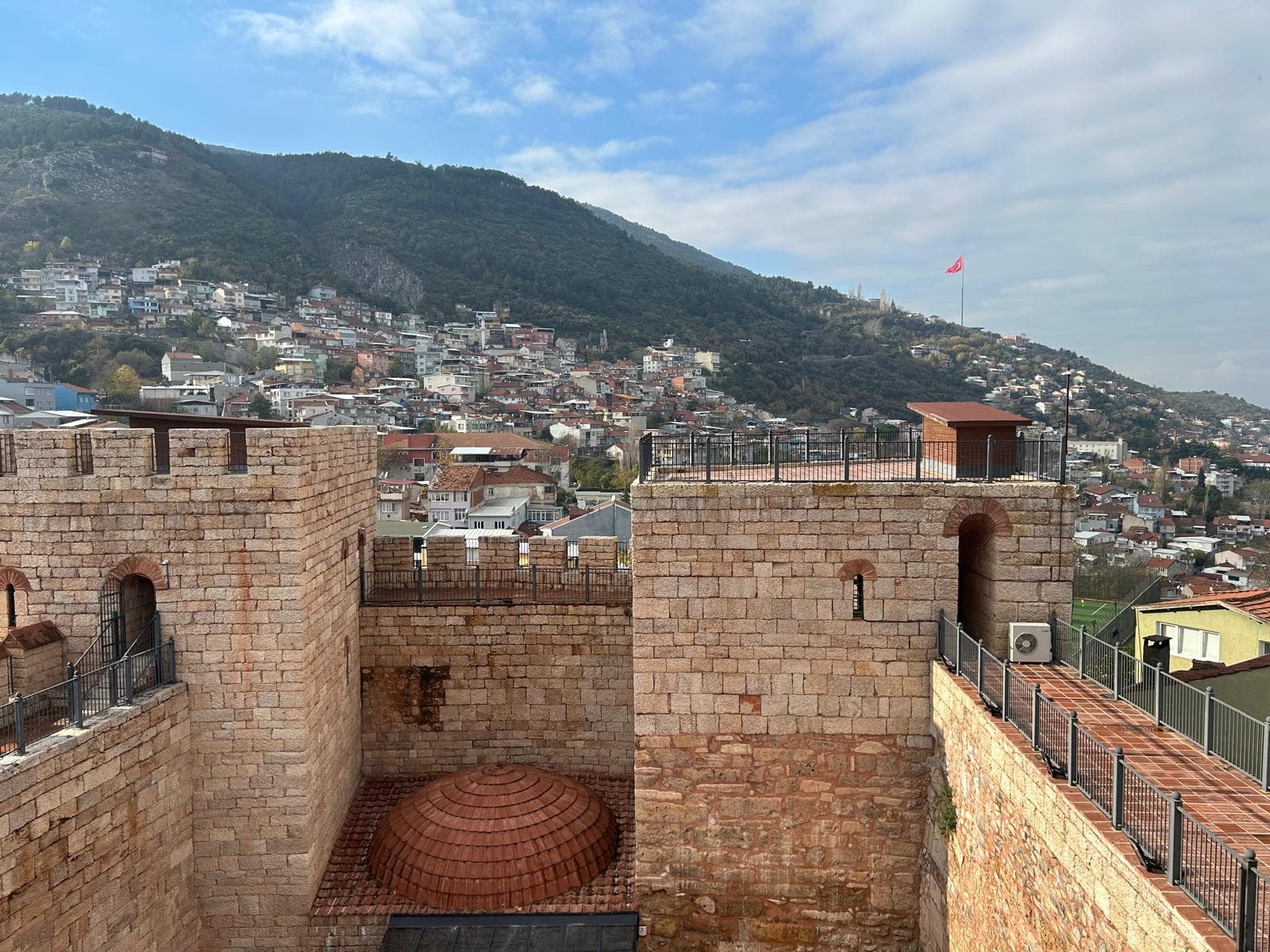 Bursa'daki tarihi Zindan Kapı surları ve arkasında uzanan şehir manzarası.